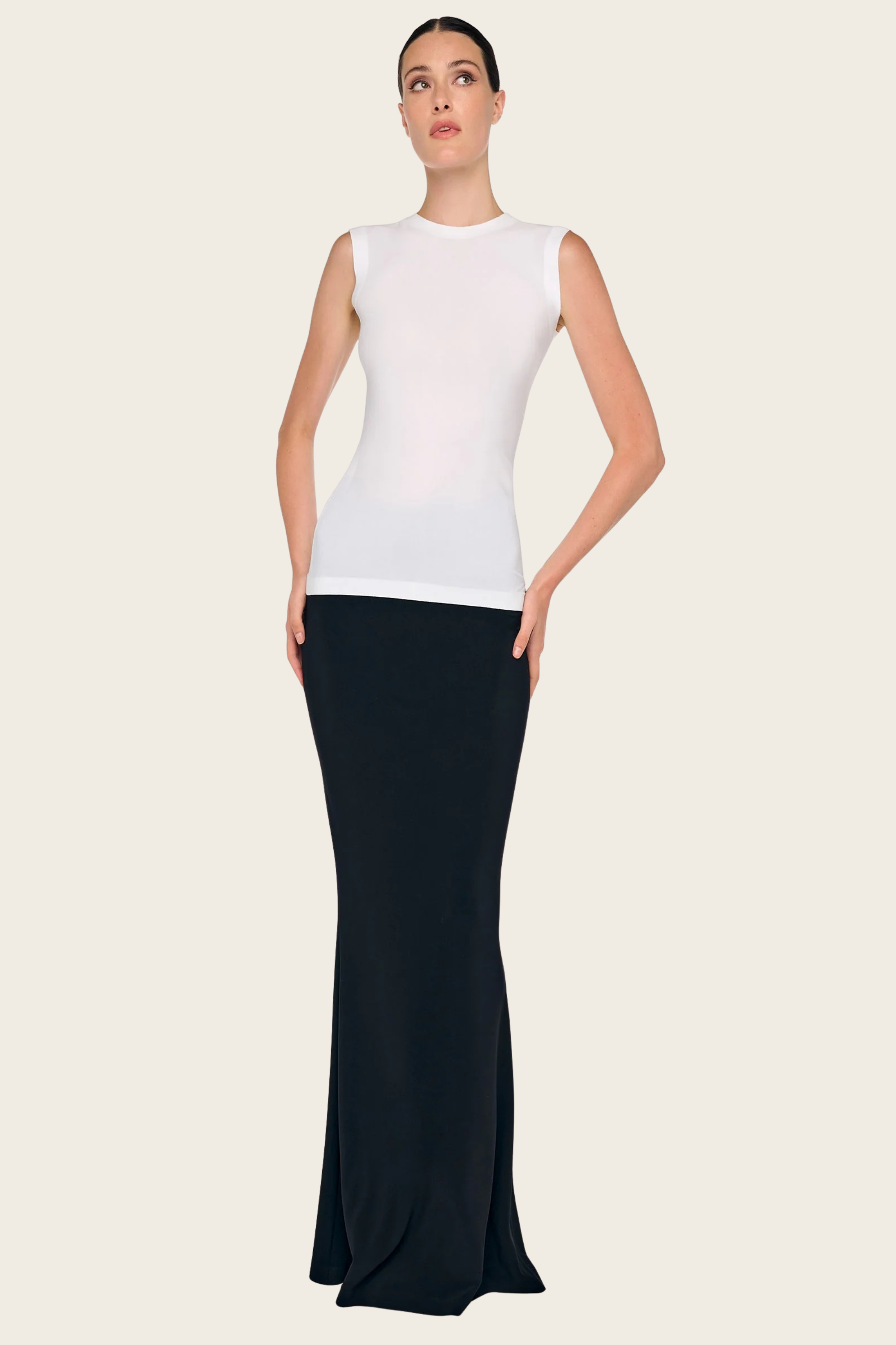 White sleeveless top by Norma Kamali with a form-fitting silhouette, styled with a black maxi skirt.