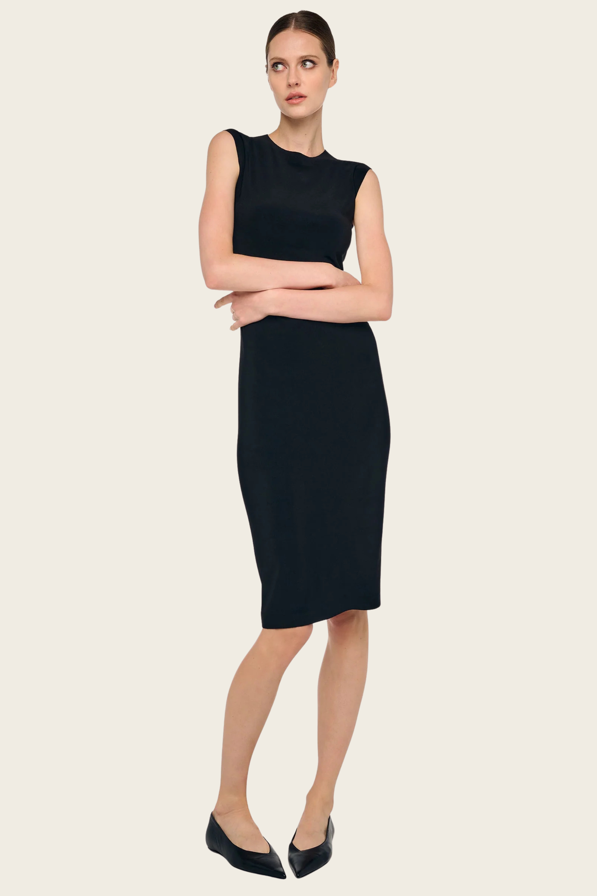 Black sleeveless dress to knee by Norma Kamali, styled with black ballet flats, on a light neutral background.