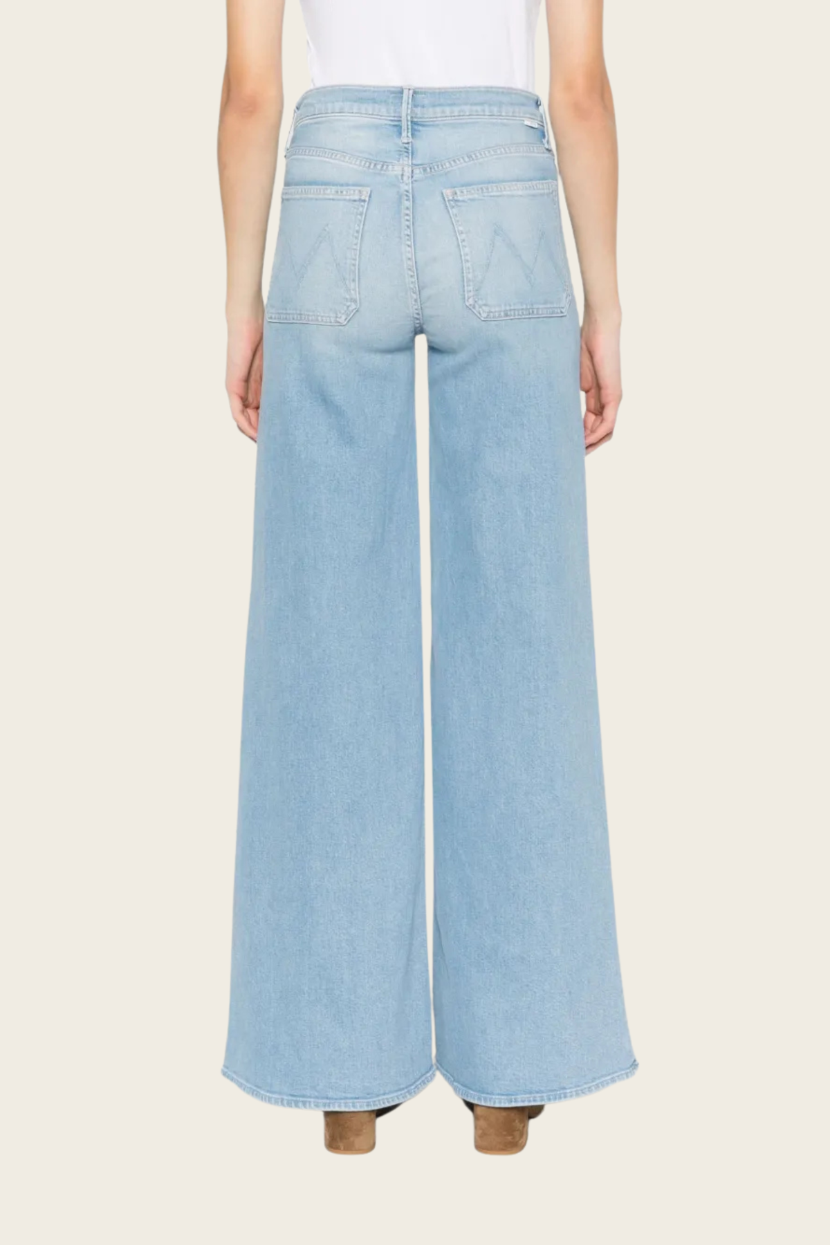 Light wash denim wide leg jeans by Mother, displayed from the back with visible patch pockets and visible brown heeled boots.