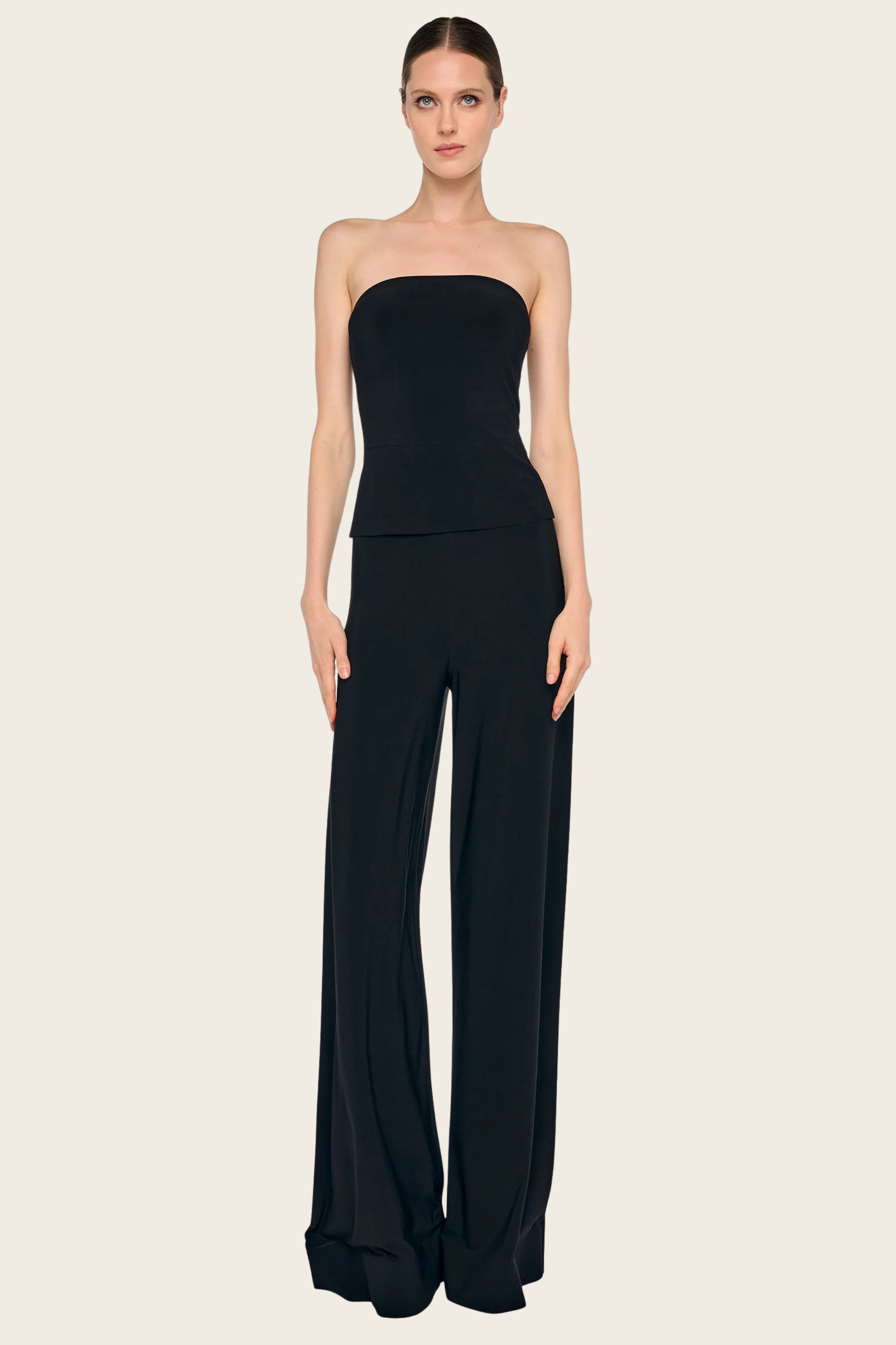 Black trouser by Norma Kamali featuring a wide leg, strapless jumpsuit style, and a layered top.