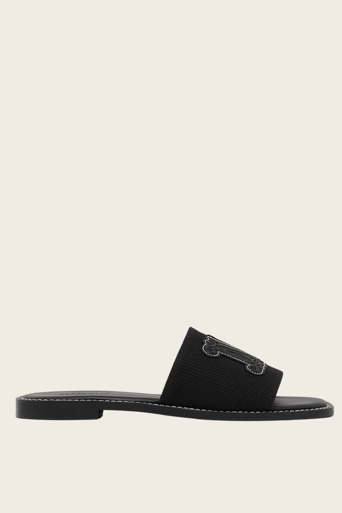 Black Geneve slide sandal by MaxMara Beachwear, side view showing a textured strap and low heel