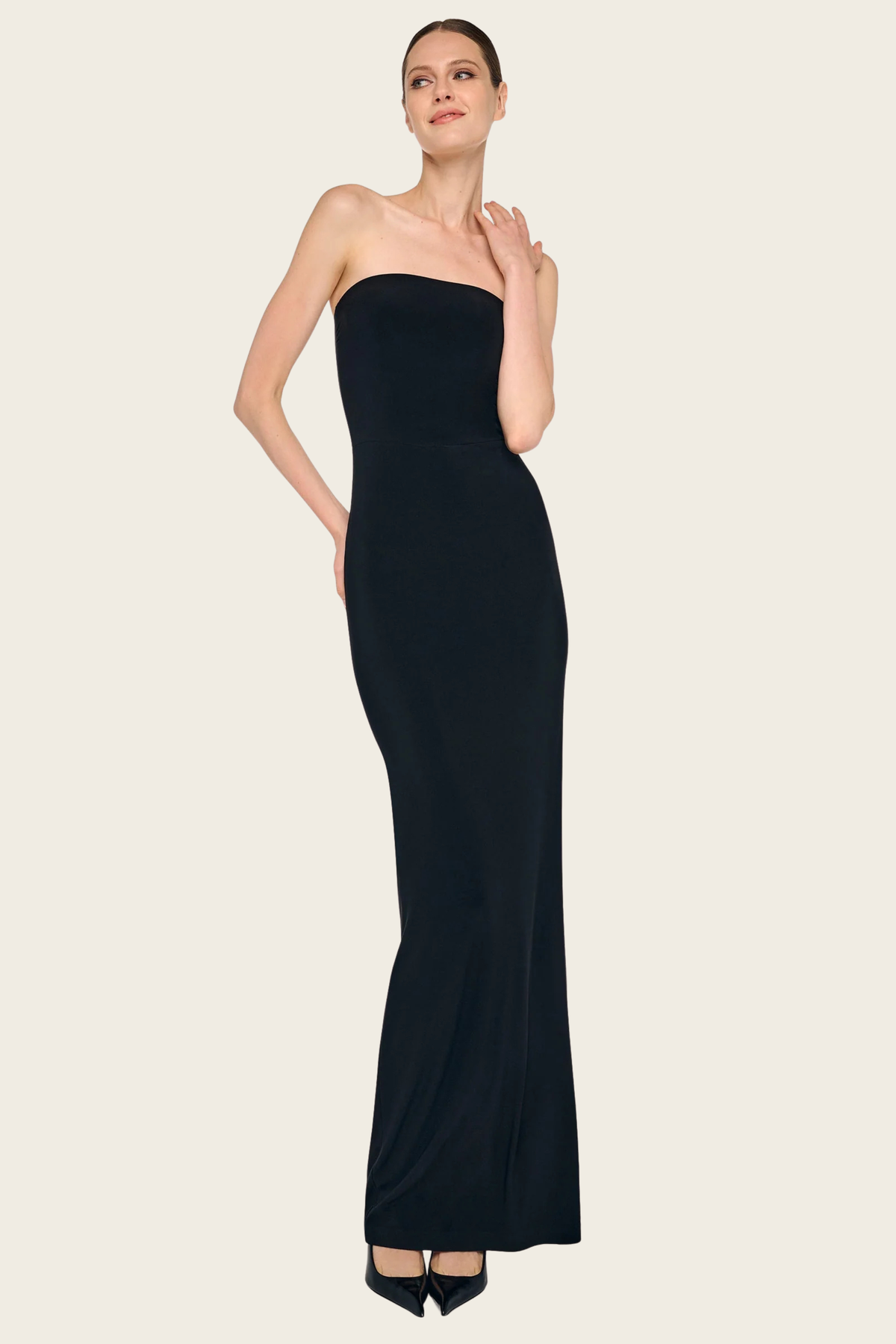 Black strapless long dress by Norma Kamali with fitted silhouette and black pumps.